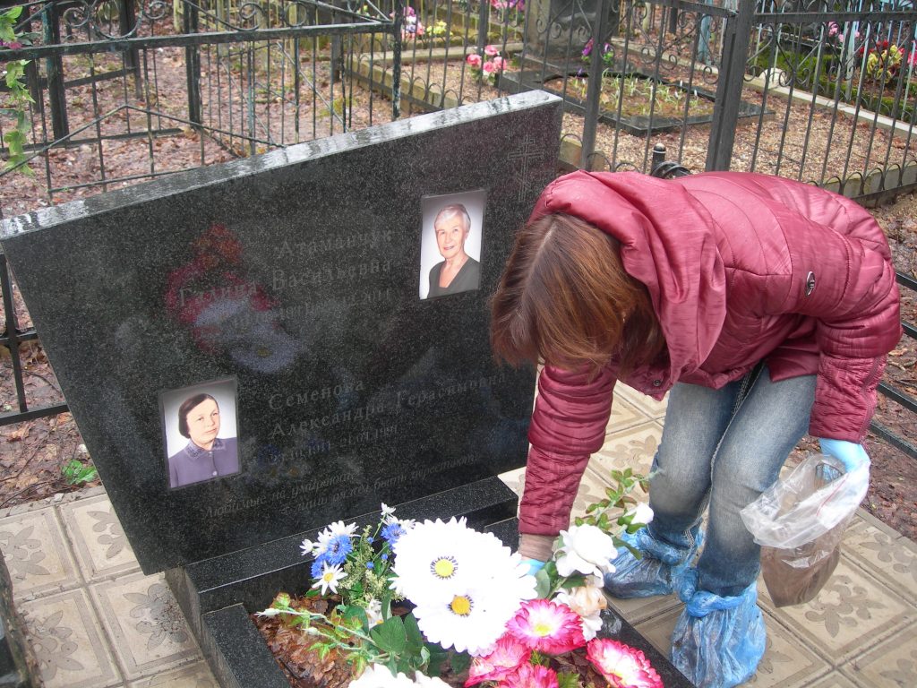 Потомки красноармейца Василия Семёнова рассыпают землю на могиле его матери